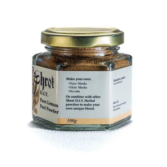 Glass jar with gold lid containing Shrot Pure Lemon Powder on a white background. Side angle.