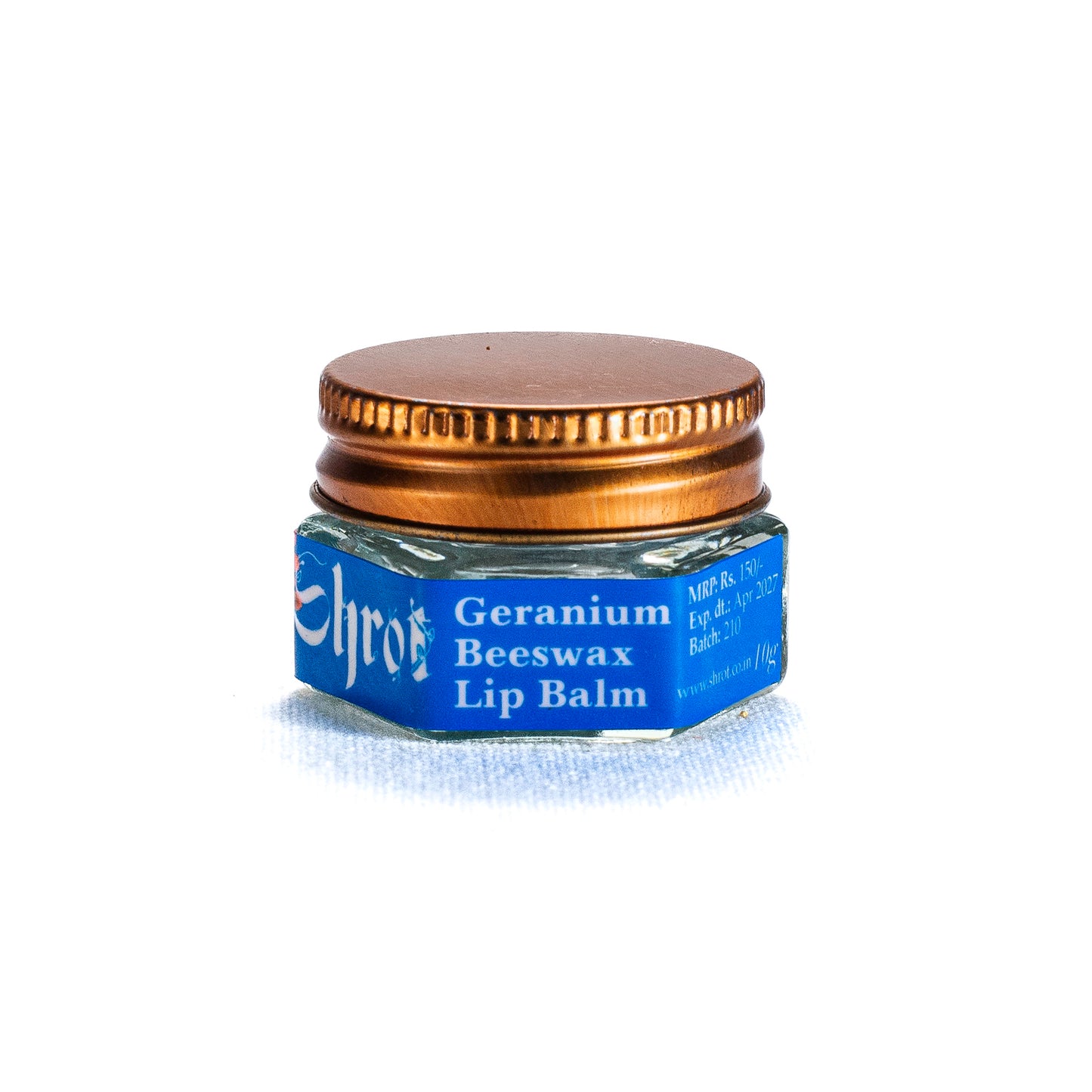 Small jar of Geranium Beeswax Lip Balm by Shrot with a blue label and gold lid on a white background. Side angle.