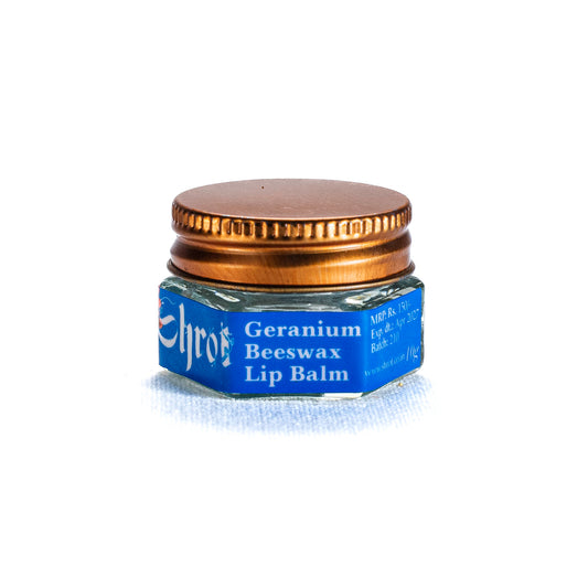Small jar of Geranium Beeswax Lip Balm by Shrot with a blue label and gold lid on a white background. Side angle.
