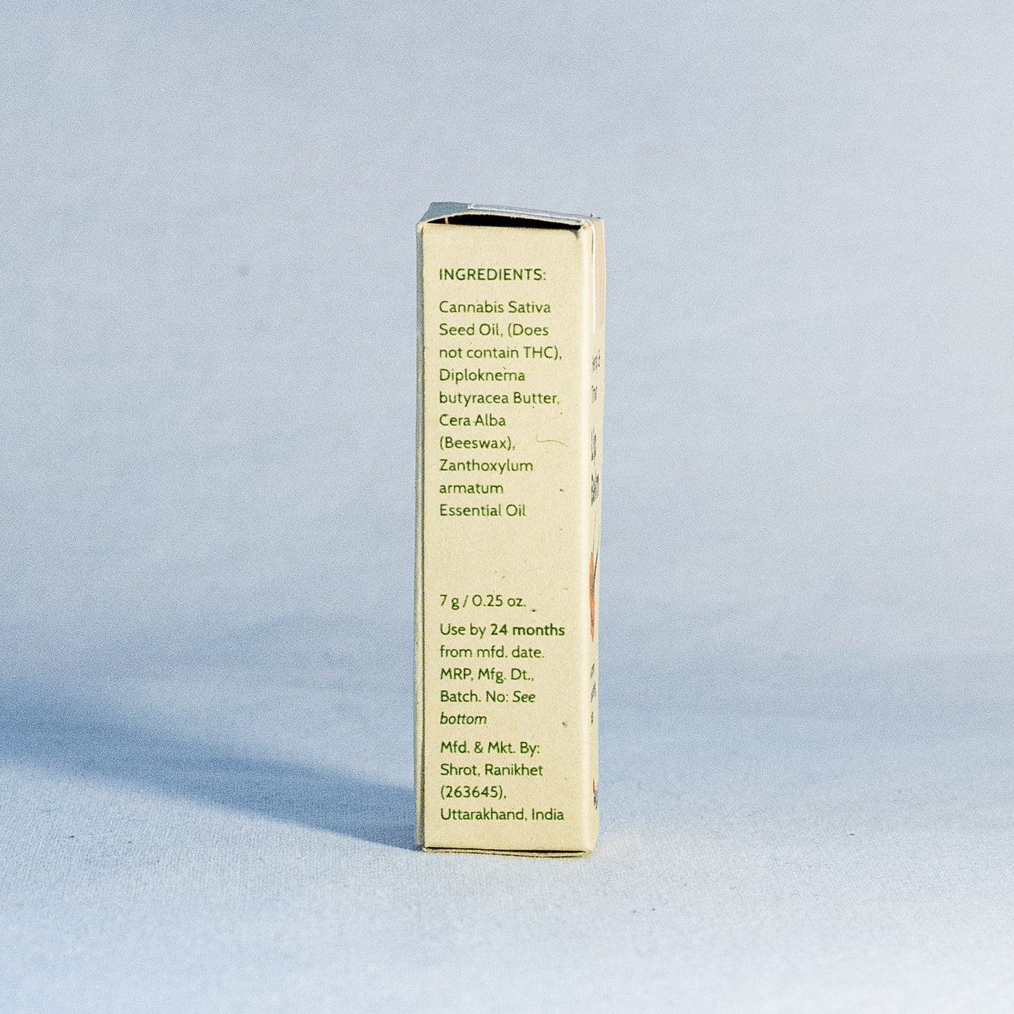 Gold-colored container with text by a natural skincare brand called Shrot on a light blue background
