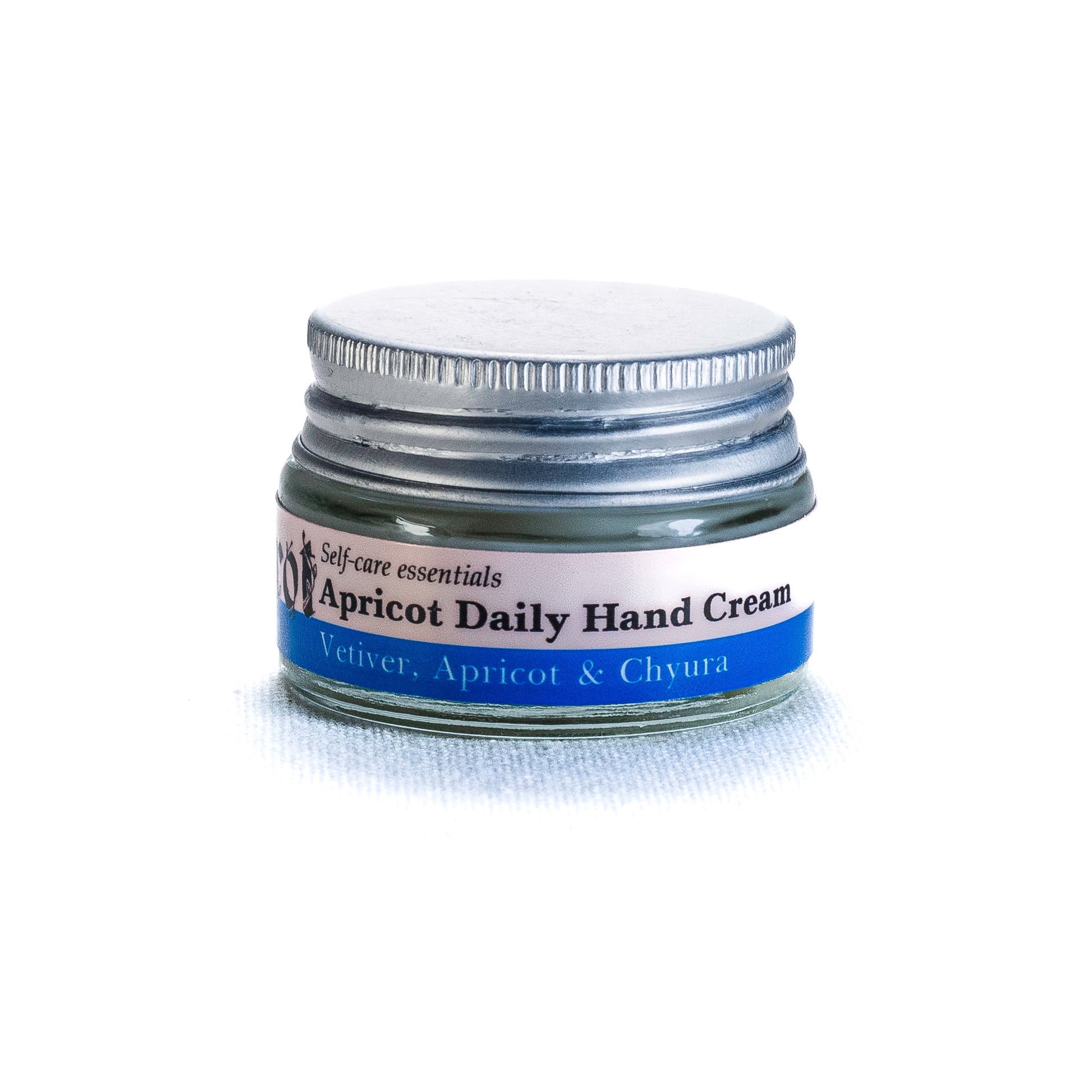 Jar of apricot daily hand cream by Shrot with a silver lid on a white background. Side view.