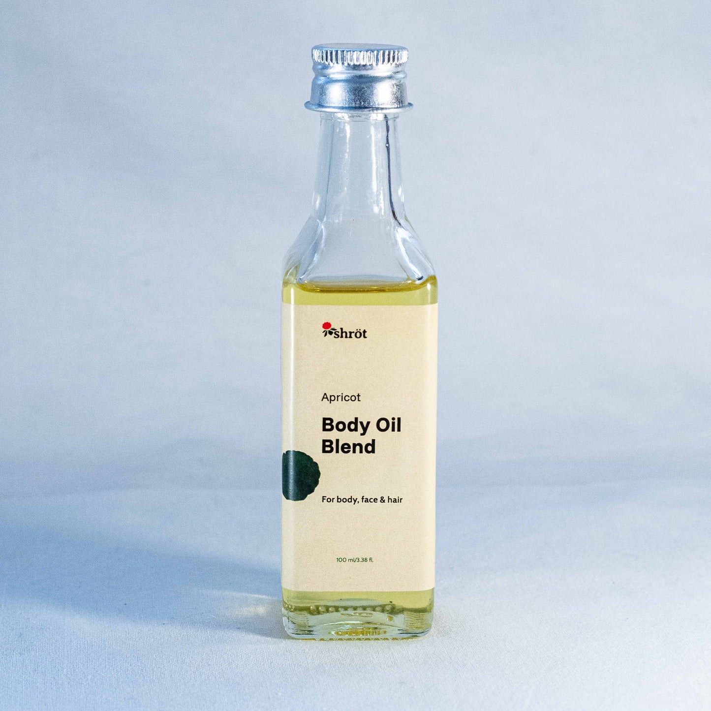 Bottle of apricot body oil blend by a natural skincare brand called Shrot on a light gray background