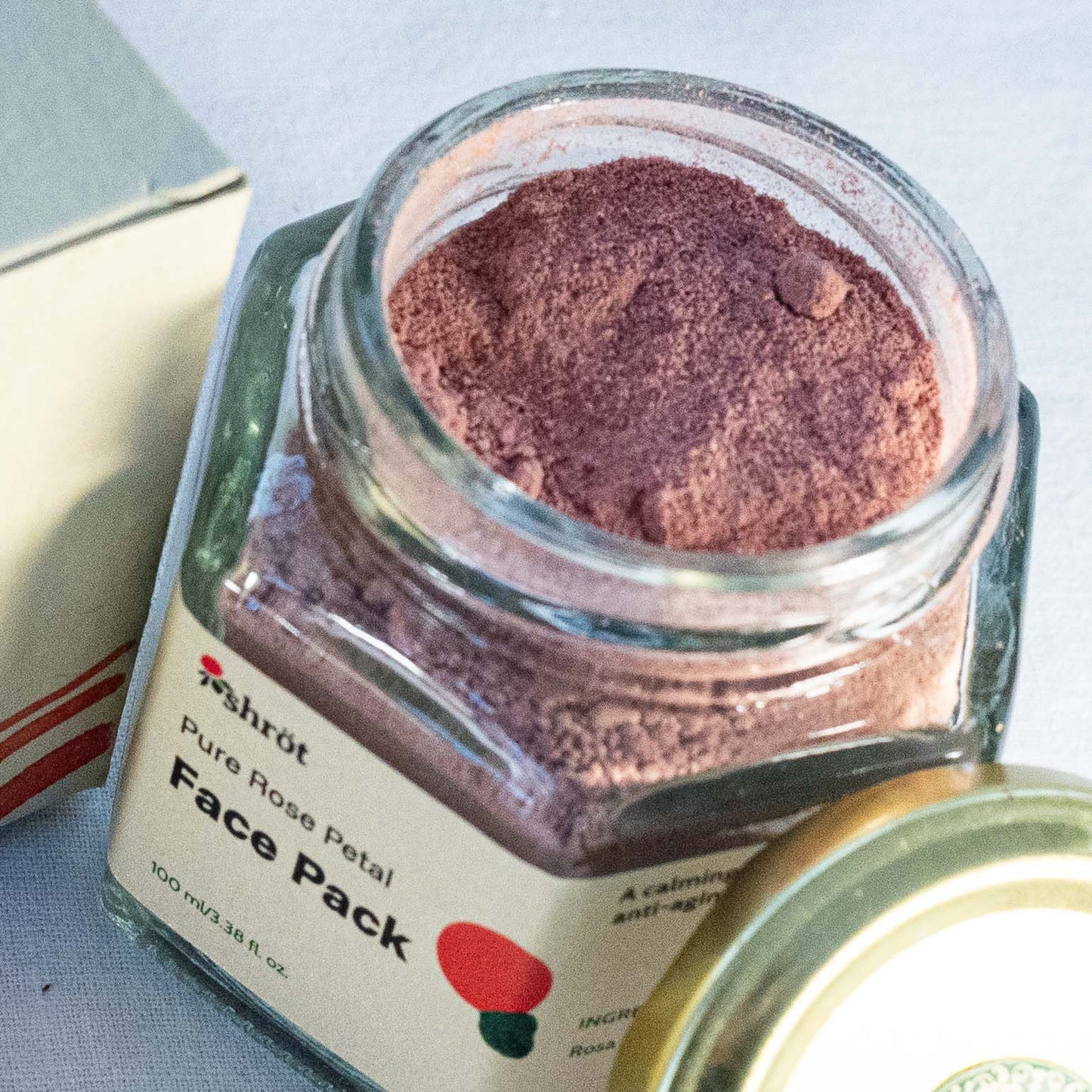 Glass jar of pure rose petal face pack with a visible label on a light background