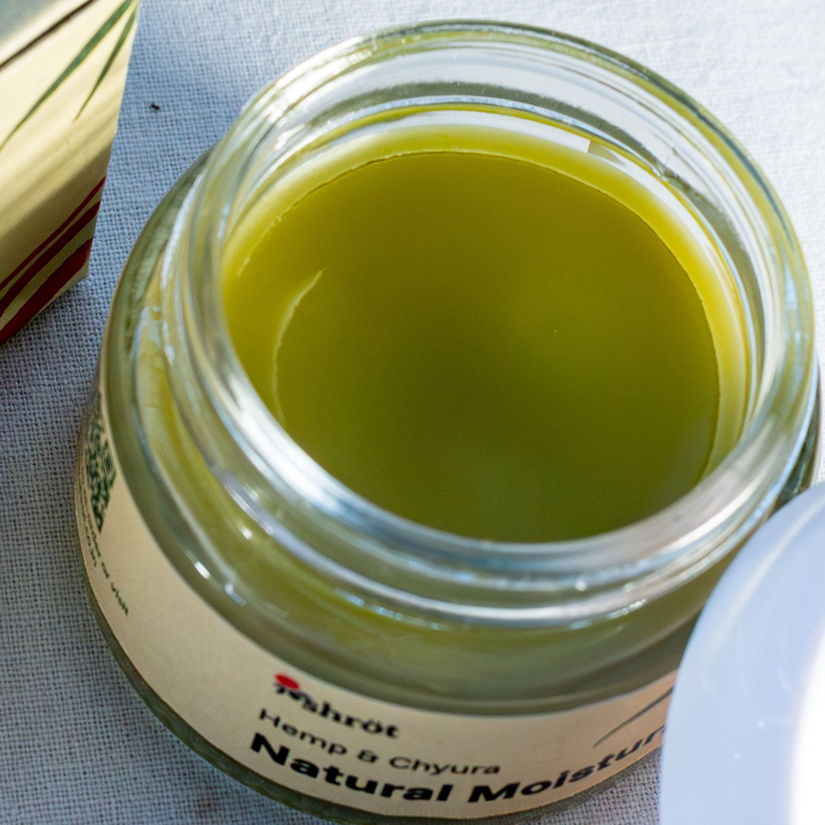 Jar of herbal cream by a natural skincare brand called Shrot with a label on a textured surface