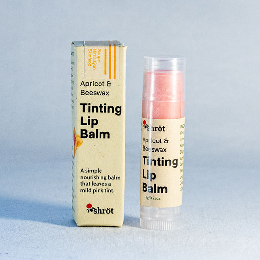 Tinting lip balm with packaging on a light blue background by a natural skincare brand called Shrot.