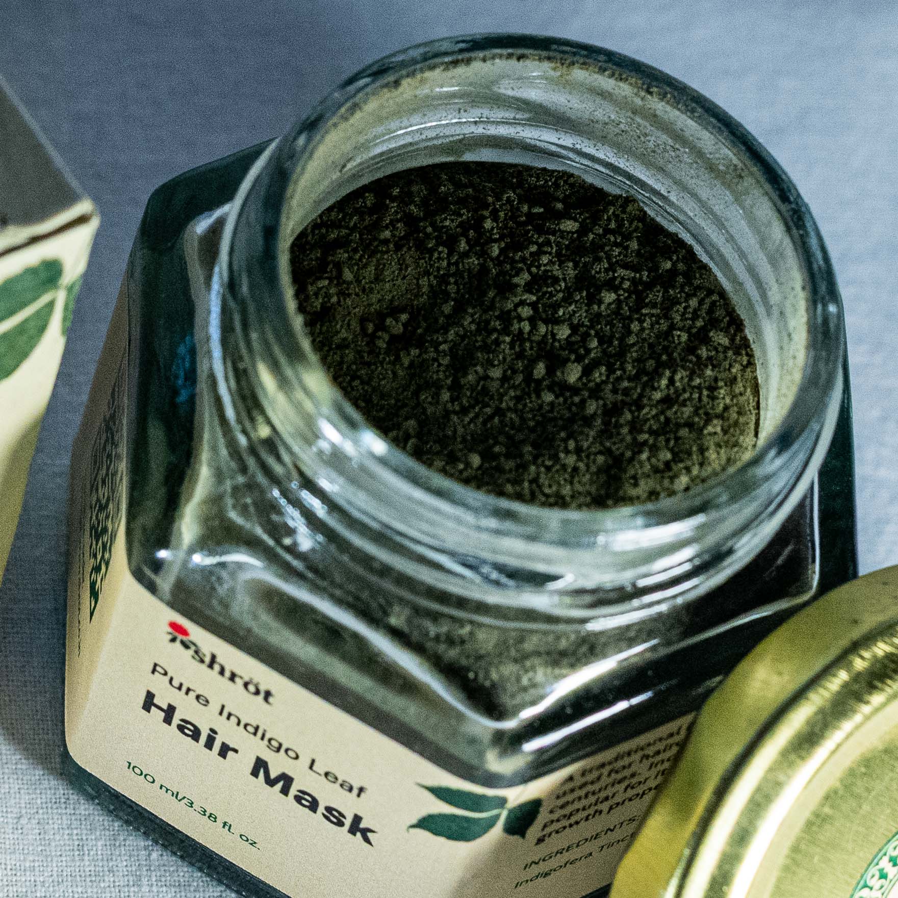 Glass jar of Shrot Pure Indigo Leaf Hair Mask with a gold lid on a gray background