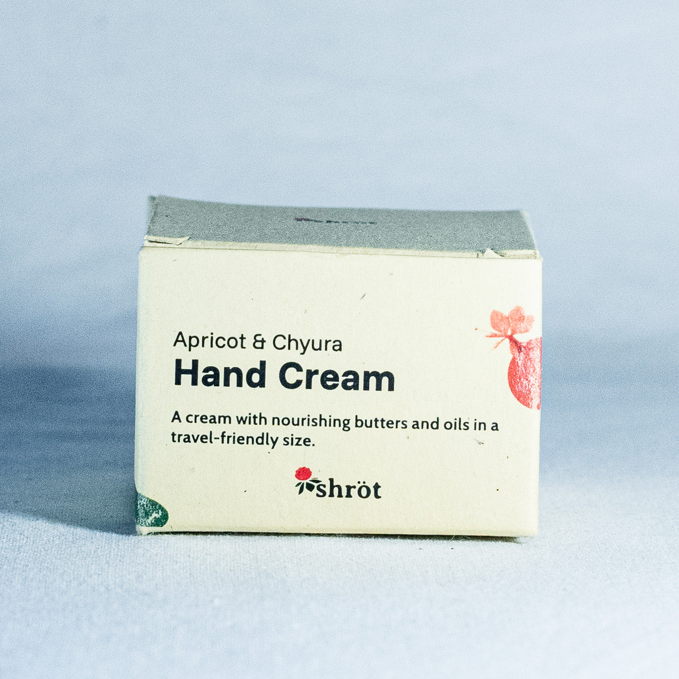 Hand cream packaging with 'Apricot & Chyura' branding by a trending Indian skincare brand called Shrot on a light blue background
