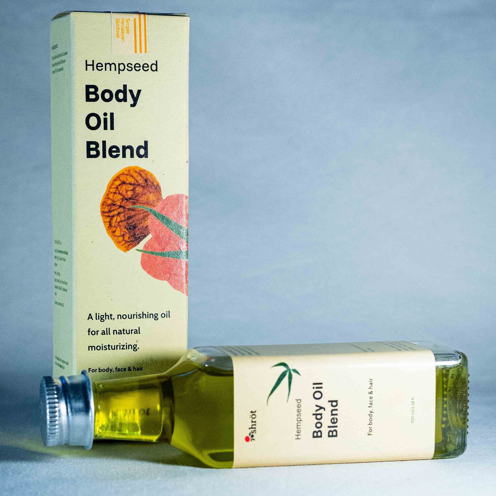 Hempseed Body Oil Blend packaging and bottle by a natural skincare brand called Shrot on a blue fabric background