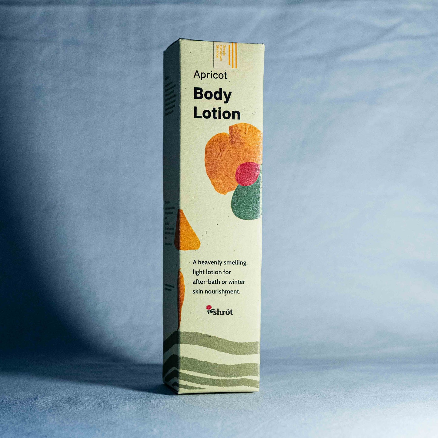 Box of apricot body lotion on a gray background by a trending Indian skincare brand called Shrot