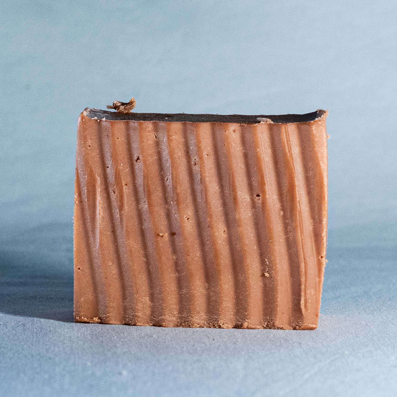 Bar of soap with a ribbed texture on a light blue background