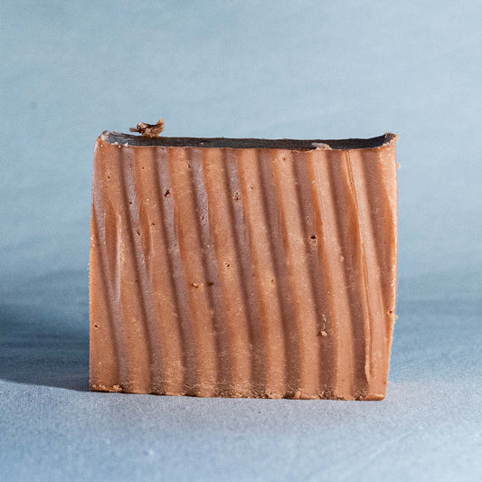 Bar of soap with a ribbed texture on a light blue background