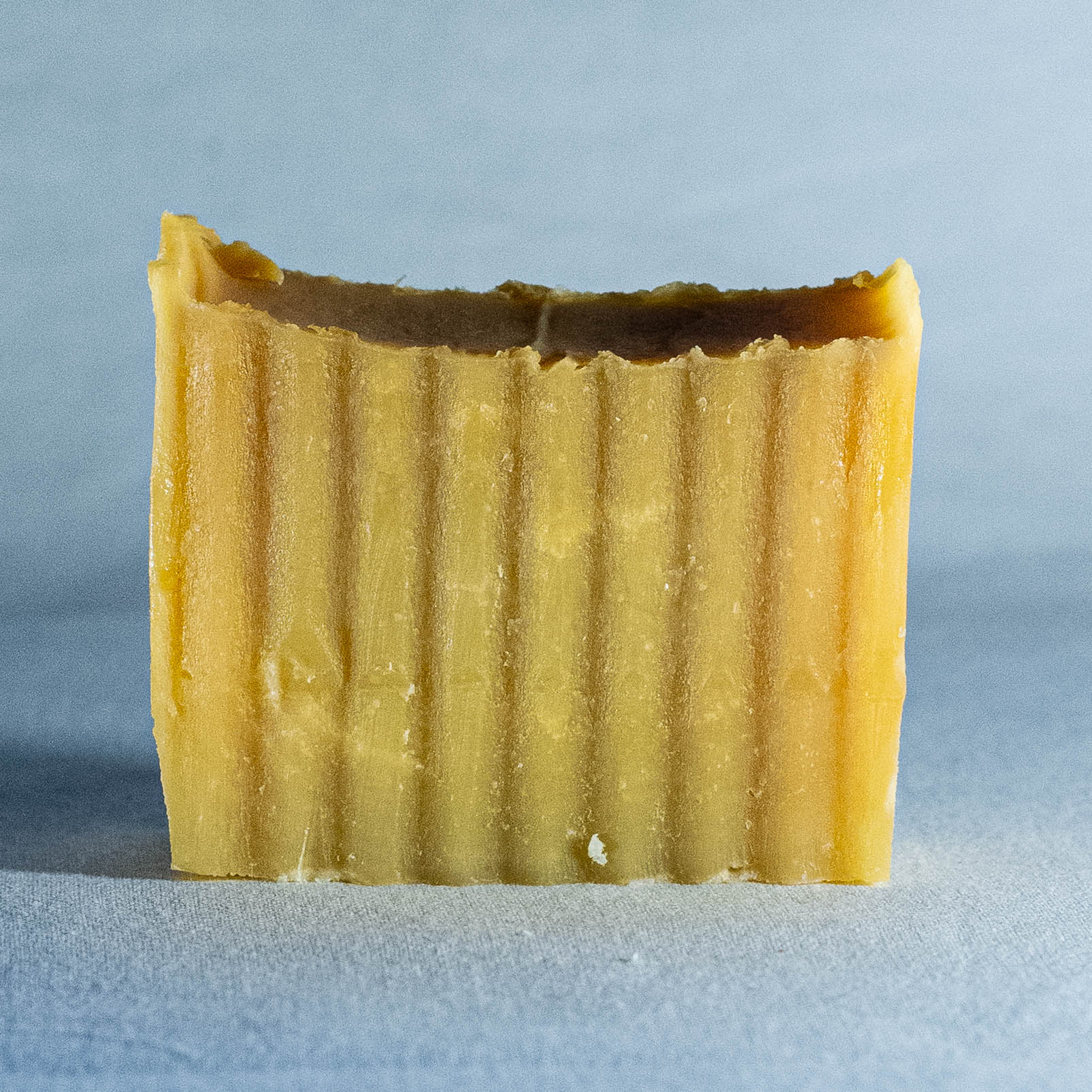 Rectangular bar of yellow soap by Shrot with textured surface on a light blue background