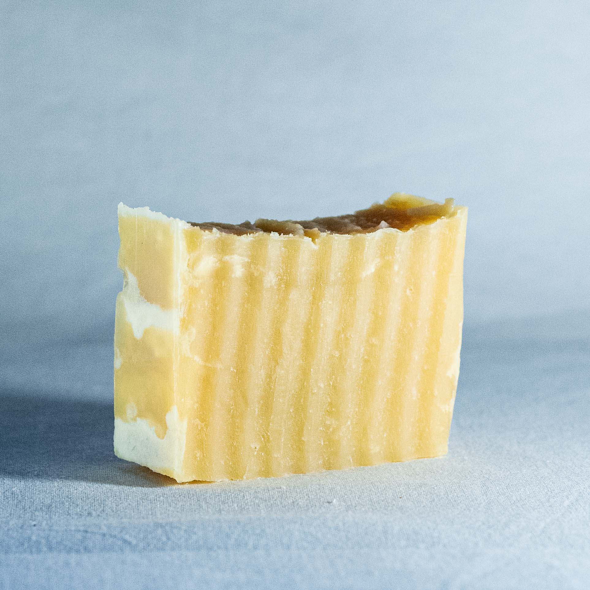 Bar of soap by Shrot with a textured surface on a light blue background