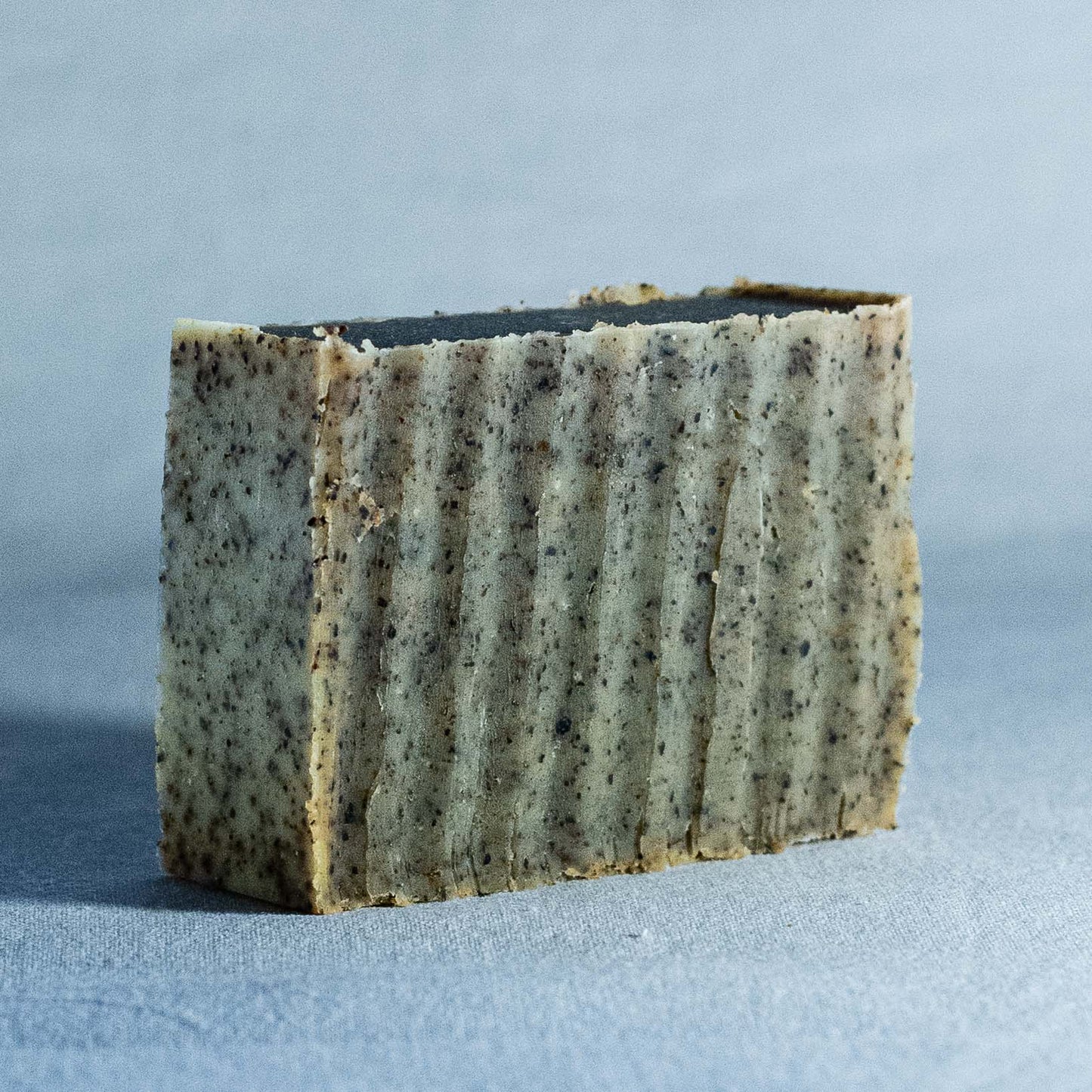 Bar of handmade soap by Shrot with a textured surface on a gray background