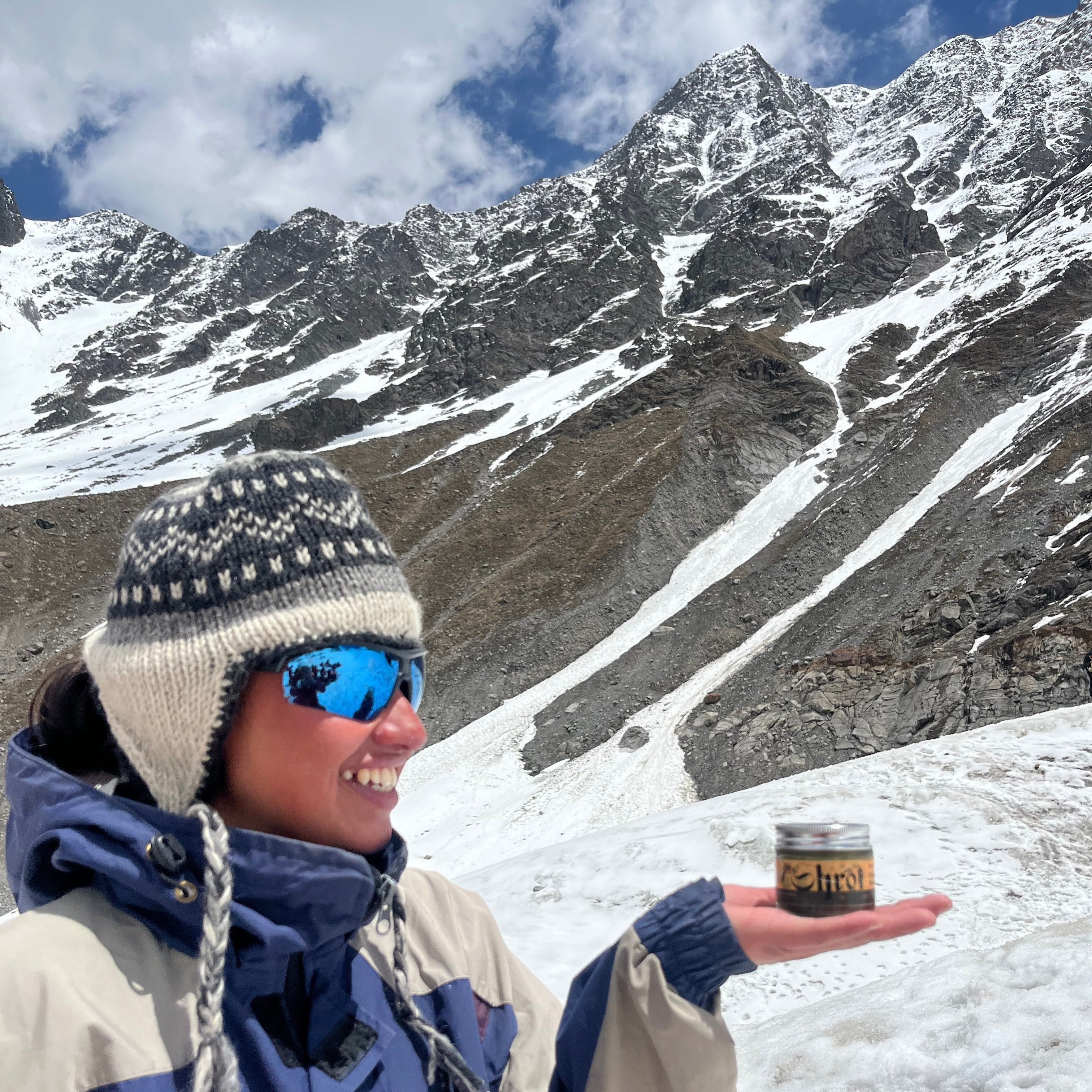 Person in a blue jacket with a logo on a snowy mountain background